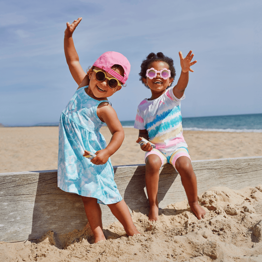 Two children enjoying Organix Oaty Bars on the beach