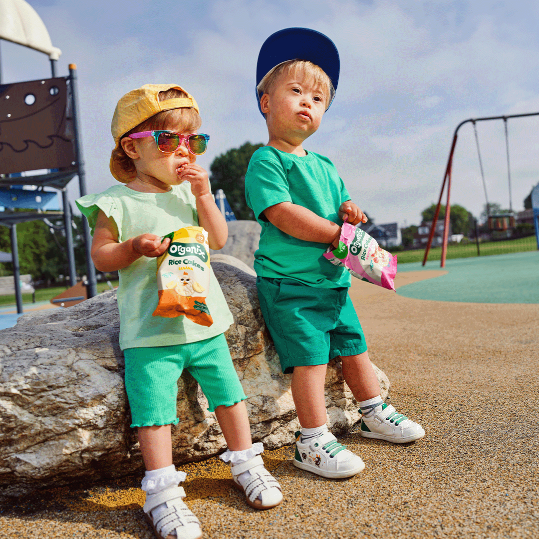 Two toddlers enjoying Organix rice cakes at a playground