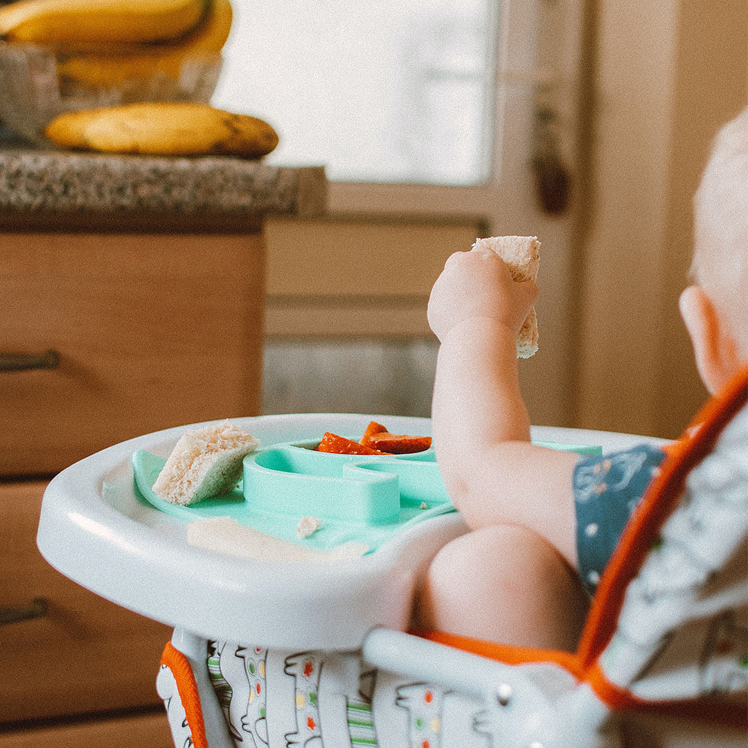 A baby exploring finger foods in a highchair